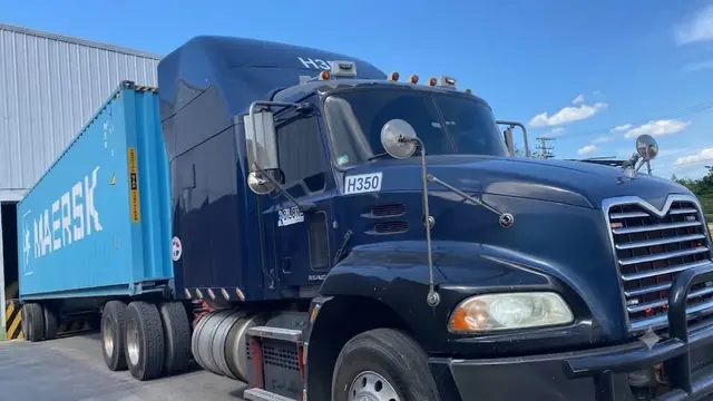 Cabezote Mack Pinnacle H350 con un contenedor Maersk junto a una nave de almacén