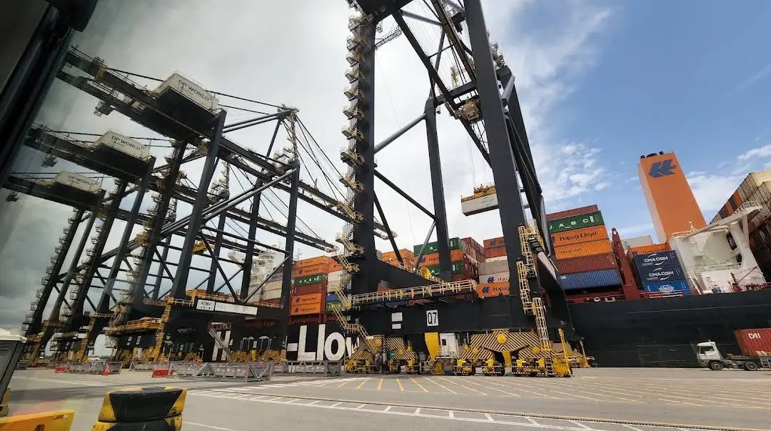 Ship-to-shore cranes at DP World Caucedo next to a container ship, seen from a truck cab